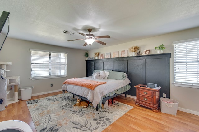 bedroom with visible vents, baseboards, a textured ceiling, and wood finished floors