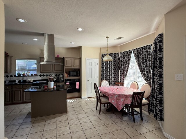 kitchen with dark countertops, visible vents, a kitchen island, island exhaust hood, and black appliances