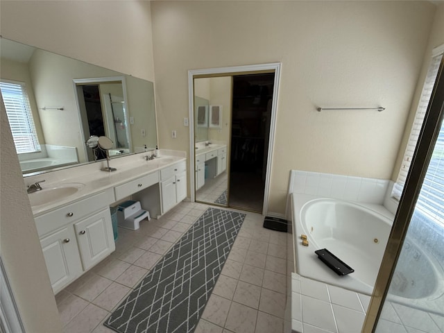 full bathroom featuring double vanity, a tub with jets, tile patterned flooring, and a sink