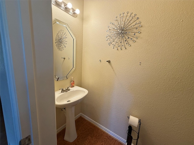 bathroom with wood finished floors, baseboards, and a textured wall