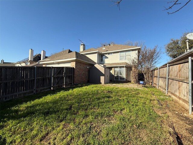 rear view of property with brick siding, a fenced backyard, and a yard