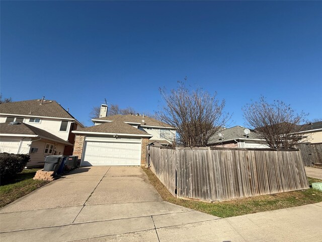 exterior space featuring fence, driveway, a chimney, a garage, and brick siding