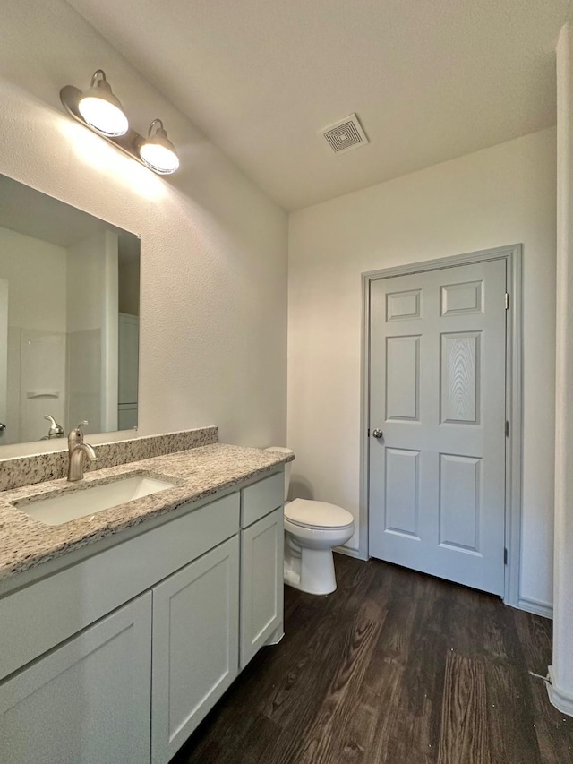 full bathroom featuring vanity, toilet, wood finished floors, and visible vents