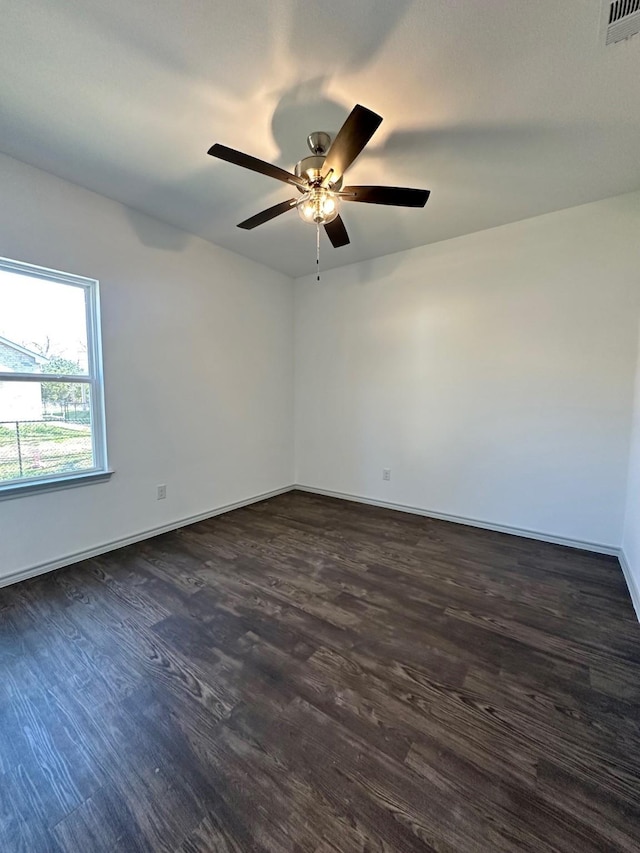 empty room featuring visible vents, ceiling fan, dark wood-type flooring, and baseboards