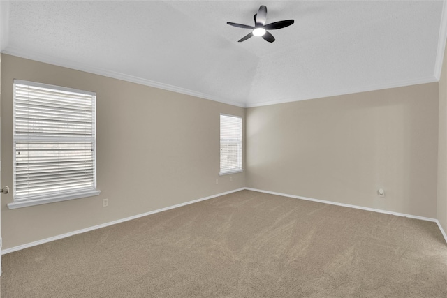 carpeted empty room with baseboards, crown molding, ceiling fan, and vaulted ceiling