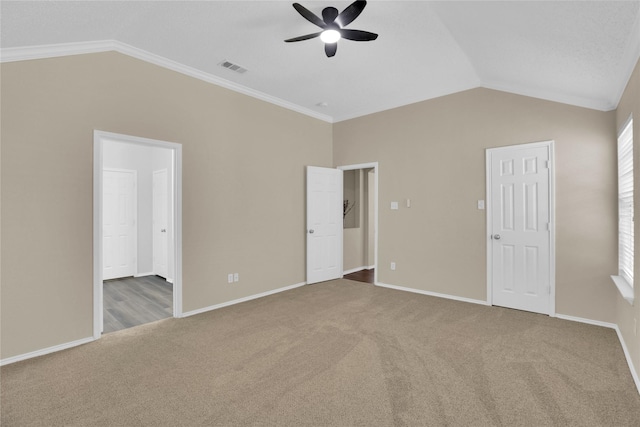 unfurnished bedroom with visible vents, carpet, and vaulted ceiling