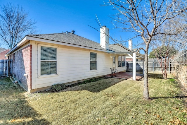 back of property featuring a yard, a patio, a fenced backyard, and a chimney