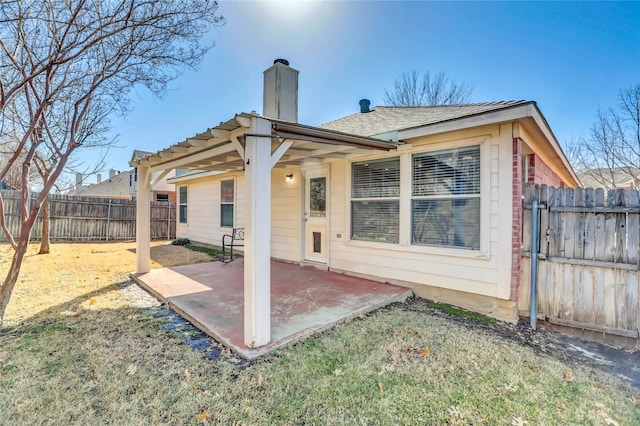 back of house featuring a patio, a fenced backyard, and a chimney