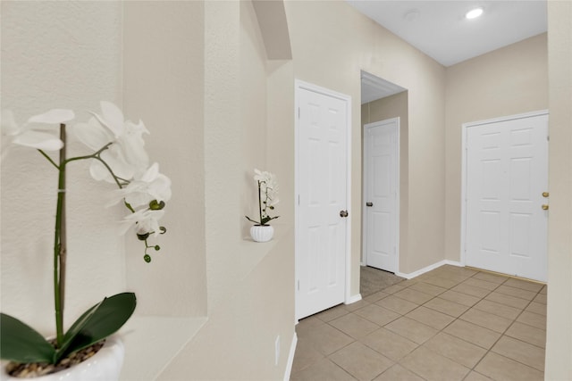 hall with baseboards and light tile patterned flooring