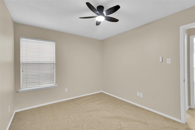 carpeted spare room featuring baseboards, a textured ceiling, and a ceiling fan