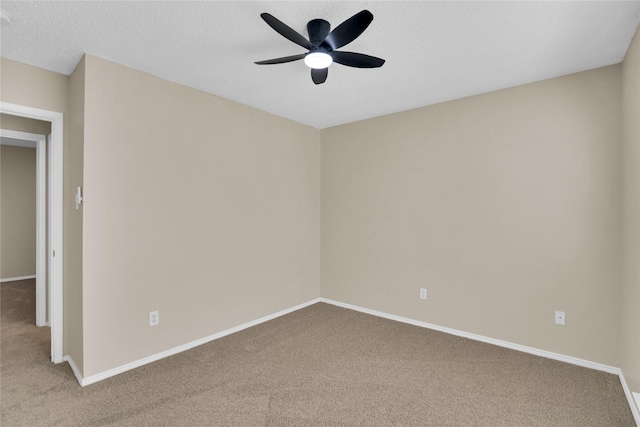 spare room with a textured ceiling, baseboards, carpet, and a ceiling fan