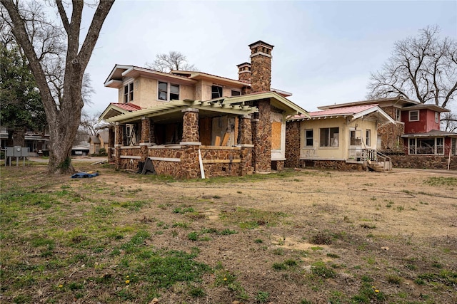 rear view of property featuring a chimney and metal roof