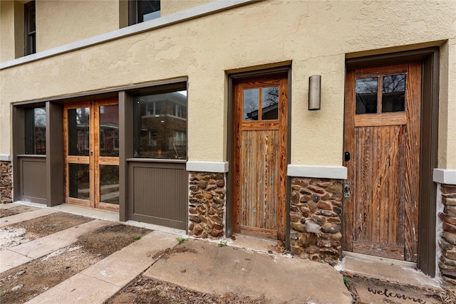 doorway to property featuring stucco siding and stone siding