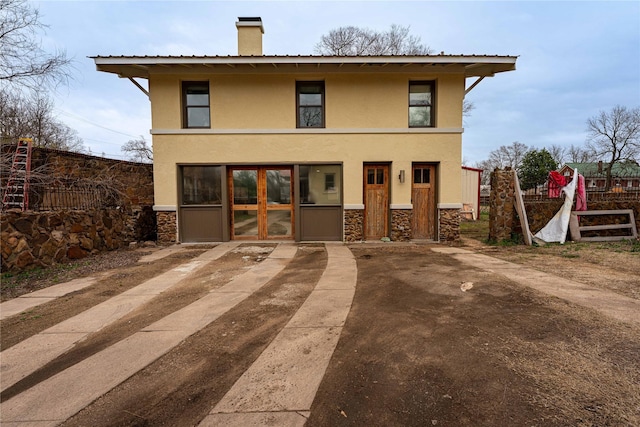 view of front of property with fence, a chimney, stone siding, and stucco siding