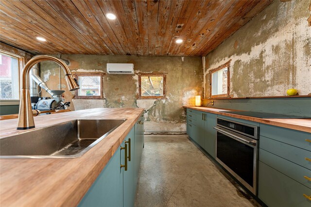 kitchen featuring stainless steel oven, wooden counters, a sink, and a wall unit AC