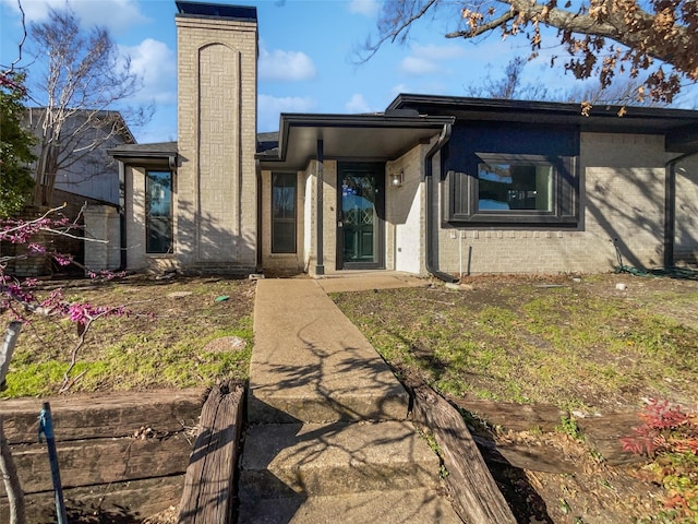 rear view of property featuring brick siding and a chimney