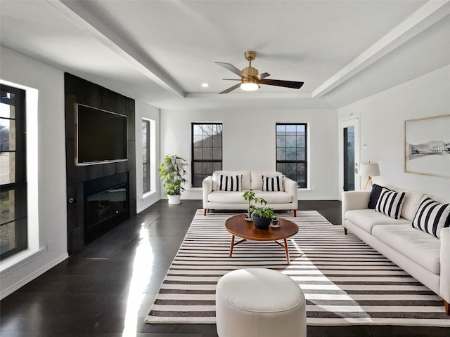 living room featuring a tray ceiling, baseboards, dark wood-type flooring, and a fireplace