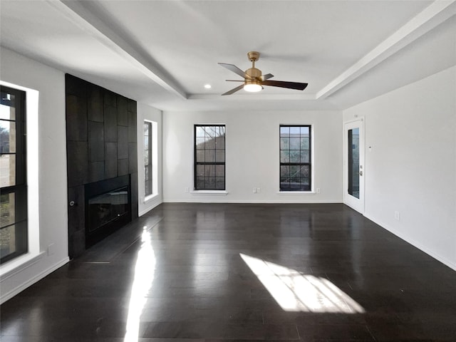 unfurnished living room with a tray ceiling, a large fireplace, baseboards, and dark wood-style floors