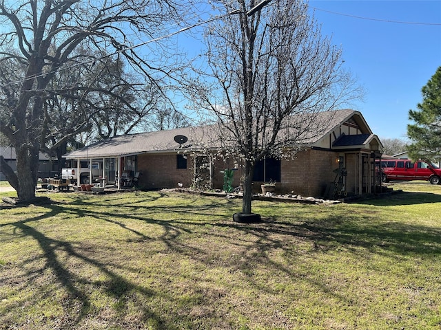 rear view of house featuring brick siding and a lawn