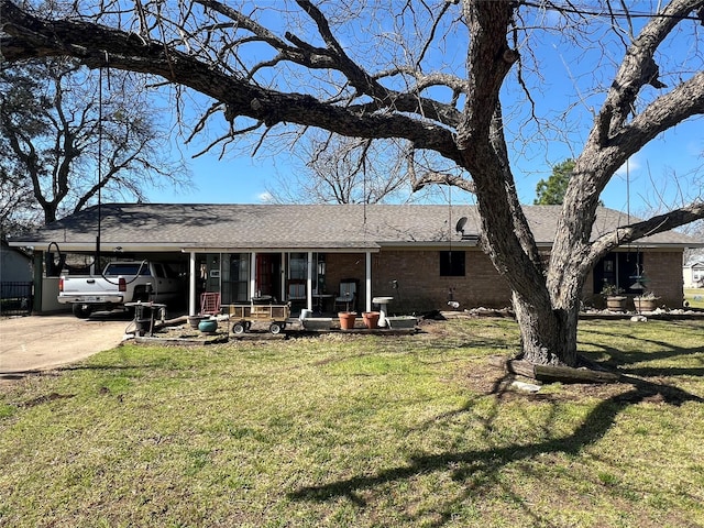 view of front facade featuring driveway, roof with shingles, a front lawn, a carport, and brick siding