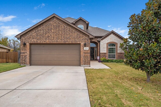 french provincial home featuring fence, driveway, a front lawn, a garage, and brick siding