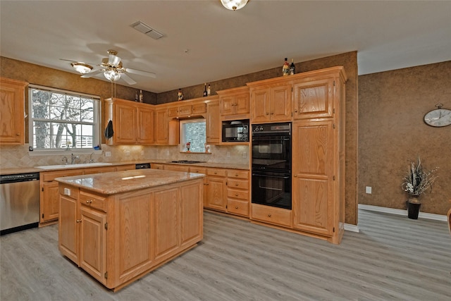 kitchen featuring visible vents, black appliances, light wood-style flooring, tasteful backsplash, and a center island