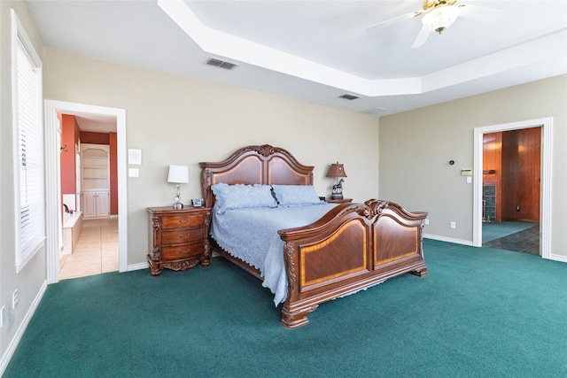 carpeted bedroom with a tray ceiling, visible vents, and multiple windows