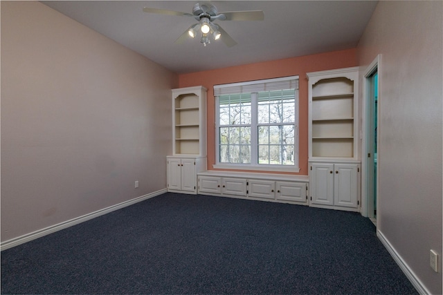 spare room with dark colored carpet, baseboards, and ceiling fan