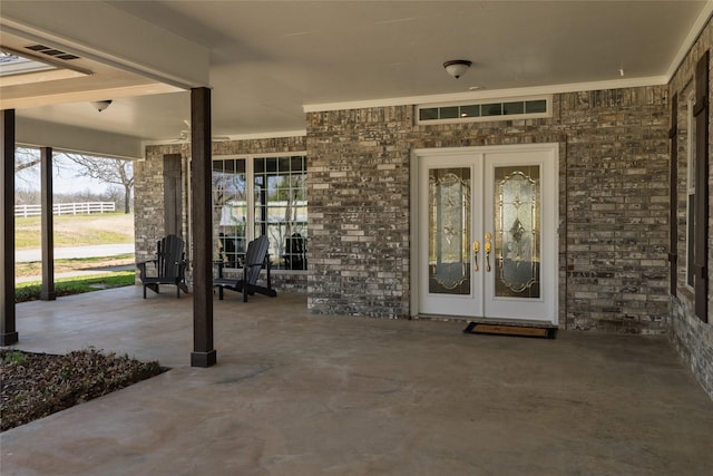 entrance to property featuring brick siding, french doors, and a porch