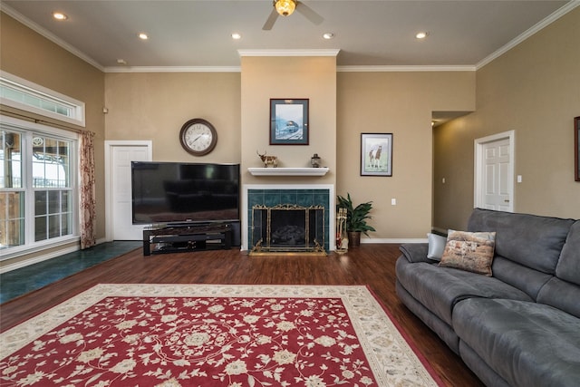 living area with crown molding, baseboards, a tiled fireplace, recessed lighting, and wood finished floors