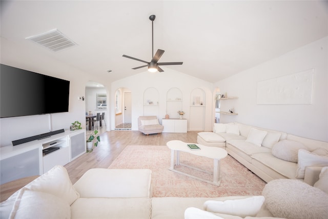 living area with visible vents, ceiling fan, light wood-type flooring, lofted ceiling, and arched walkways