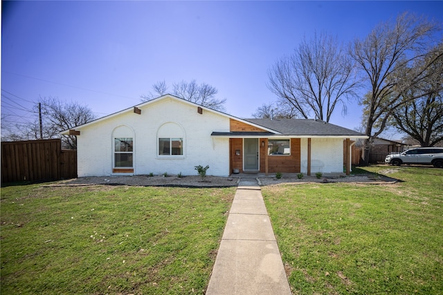 view of front of property with brick siding, a front yard, and fence