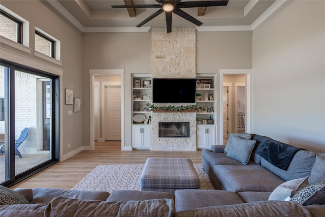 unfurnished living room featuring baseboards, light wood-style flooring, a fireplace, a towering ceiling, and a ceiling fan