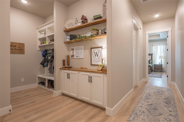 corridor with light wood-style flooring, recessed lighting, and baseboards