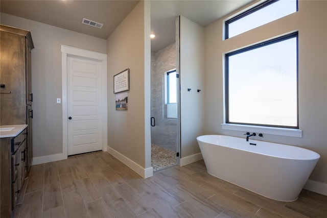 full bathroom featuring vanity, a stall shower, a wealth of natural light, and wood finish floors