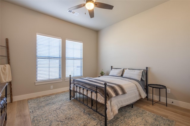 bedroom featuring visible vents, a ceiling fan, baseboards, and wood finished floors