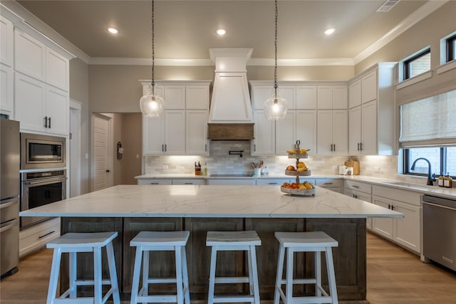 kitchen featuring a sink, a kitchen bar, white cabinetry, and stainless steel appliances