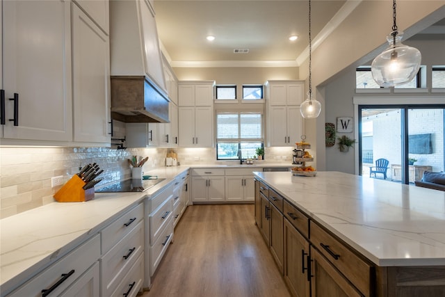 kitchen featuring black electric cooktop, a kitchen island, visible vents, and white cabinetry