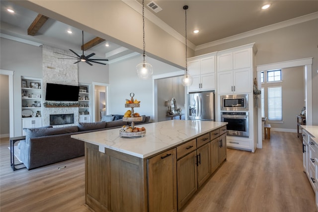 kitchen with visible vents, light wood-style flooring, stainless steel appliances, white cabinets, and a fireplace