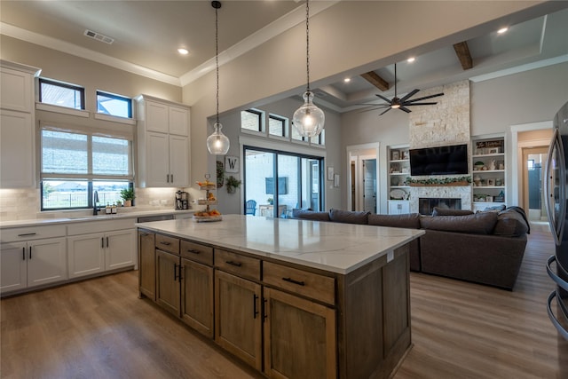 kitchen with visible vents, dark wood-type flooring, a sink, plenty of natural light, and a stone fireplace