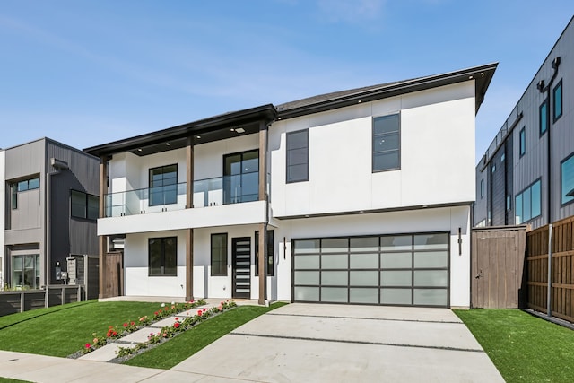 view of front facade featuring a balcony, fence, stucco siding, a front lawn, and concrete driveway