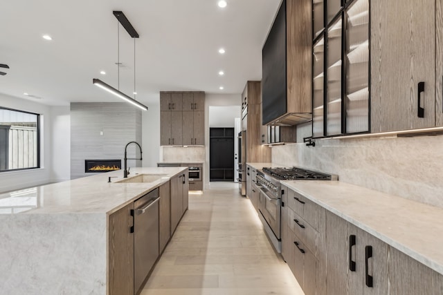 kitchen with a sink, a large island, modern cabinets, premium appliances, and a large fireplace