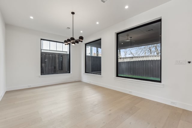 empty room featuring recessed lighting, baseboards, an inviting chandelier, and wood finished floors