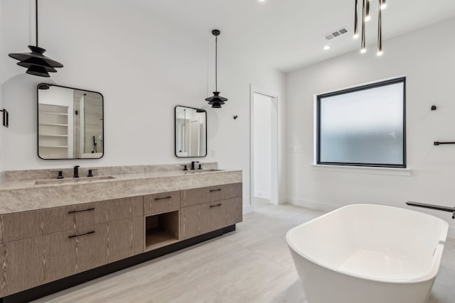 full bathroom featuring double vanity, visible vents, a freestanding bath, and a sink