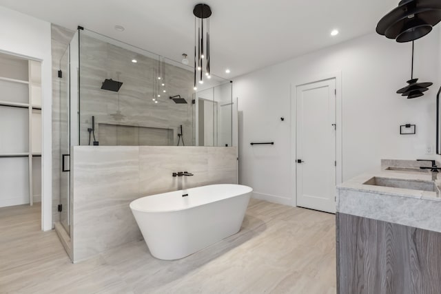 full bathroom featuring recessed lighting, a stall shower, a freestanding bath, and vanity