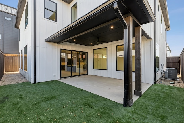 rear view of property featuring a patio, cooling unit, fence, a yard, and board and batten siding