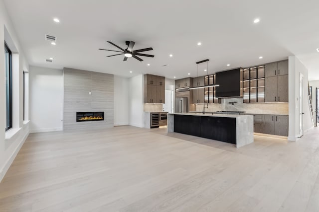 kitchen with ceiling fan, light countertops, high end refrigerator, modern cabinets, and a kitchen island with sink