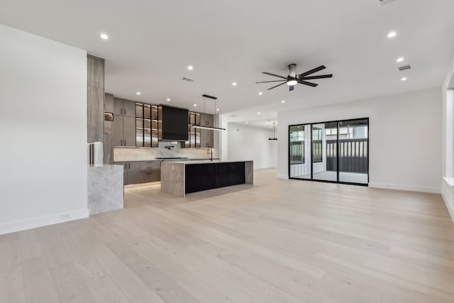 kitchen featuring a sink, open floor plan, modern cabinets, and an island with sink