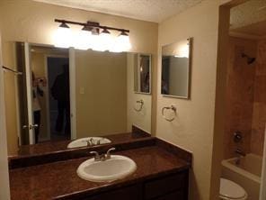 bathroom with vanity, shower / tub combination, toilet, and a textured ceiling