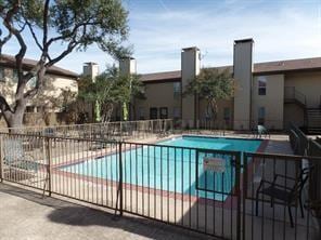 community pool with a patio area and fence